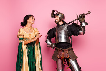 Fototapeta premium A joyous romantic portrayal of a medieval couple in regal attire against a bright pink background highlighting classic and vintage elegance