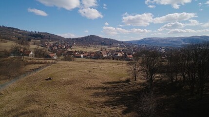 Fototapeta premium Aerial view of village nestled in valley, sunny day