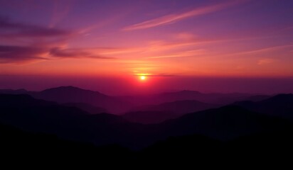Obraz premium Vibrant sunset paints the sky with purple hues and an orange glow, silhouetting mountains in a panoramic, ethereal landscape. A breathtaking twilight scene of nature's serene beauty.