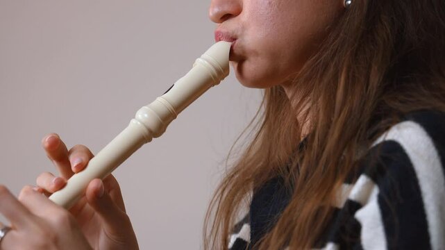 Young woman musician playing recorder flute, seen in split-screen montage against neutral background, creating visually engaging sequence
