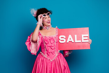 Elegant woman in a pink baroque dress holding a sale sign against a blue background in vintage style