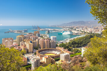 Malaga, seaside city in Andalusia, Spain, Europe. Coastal city panorama with harbor, bullring, and cityscape under a clear blue sky.