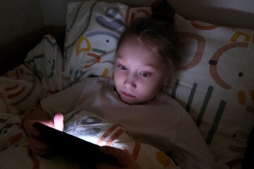 A girl plays an online game on her smartphone at night. Children's dependence on smartphones....