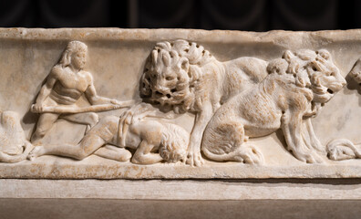 Close-up on ancient marble wall decorated with carved sculptures of lions eating prisoners