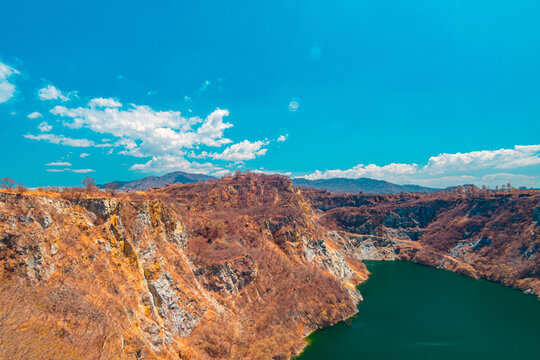 Infrared photography, a vast landscape featuring steep, rocky cliffs surrounding a greenish-blue body of water of quarry