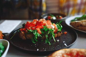 Delicious open-faced sandwich with fresh tomatoes and arugula on a rustic plate
