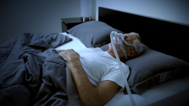 Mature adult sleeping at night while wearing a CPAP mask to treat his Sleep Apnea.