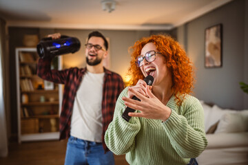 women and man have fun at home dance with loudspeaker and sign on mic