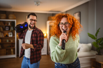 women and man have fun at home dance with loudspeaker and sign on mic