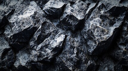 Fototapeta premium Textured surface of dark, rugged rock formation showcasing sharp edges and deep shadows.