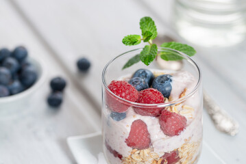 Healthy dessert - raspberries and blueberries layered with yogurt in glasses - close up