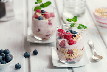 Healthy muesli - raspberries and blueberries layered with yogurt in glasses