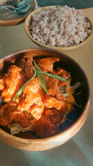 A wooden bowl of saucy fried oyster mushroom garnished with paired with a bowl of brown rice for a healthy home cooked vegan meal