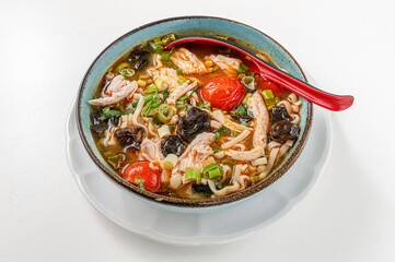 Ramen soup with filleted chicken, oriental vegetables, Thai mushrooms and ginger isolated on white background, traditional Thai recipe with chicken broth served on bowl