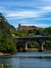 Naklejka premium Historic Church and Stone Bridge in a Scenic River Landscape