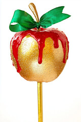 golden candy apple on a glitter stick with red glaze dripping, isolated on white background