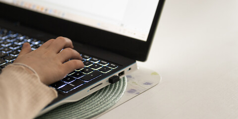 A schoolboy is working online on a white laptop. A concept of cloud learning