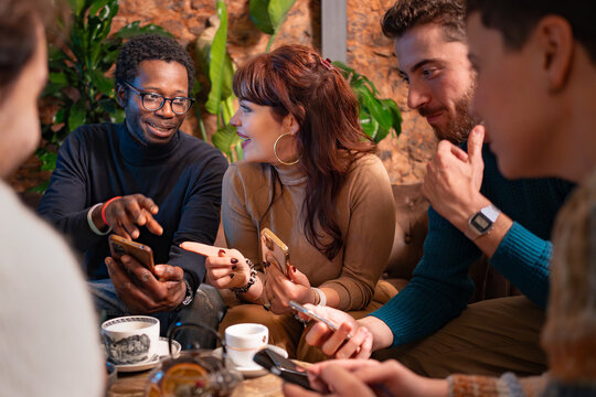 Multiracial friends socializing and using smartphones at a cozy café