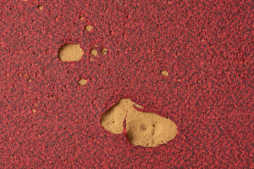 close-up of damaged red fabric pillow or cushion covers with multiple holes expose yellow foam...