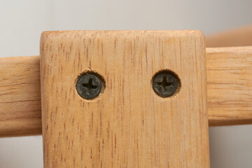 close-up macro view of countersunk black phillips head metal screws driven into the wood to flush...