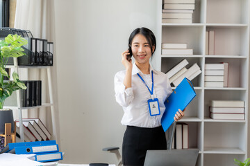 Confident and Connected: A young professional woman in a white shirt and black skirt confidently...