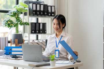 Focused and Organized: A confident young businesswoman smiles as she manages her files and works on...