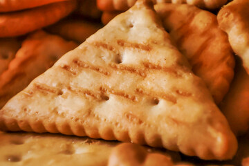 Close-up of crispy triangular biscuits with a golden hue, perfect for snack lovers. Ideal for culinary themes and food photography.