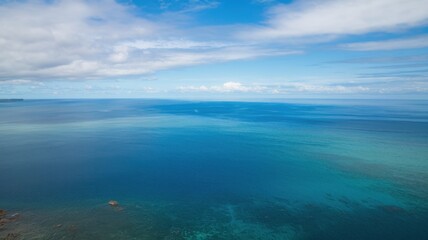 Obraz premium A stunning aerial view of the tranquil blue waters, merging various shades of turquoise and deep blue under a bright sky.