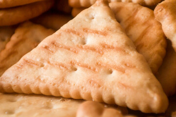 Close-up of golden triangular biscuits showcasing their crispy texture and warm hues, ideal for food-related projects.