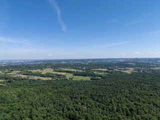 Aerial view of a lush green landscape with rolling hills under a bright blue sky, showcasing nature's beauty and tranquility.