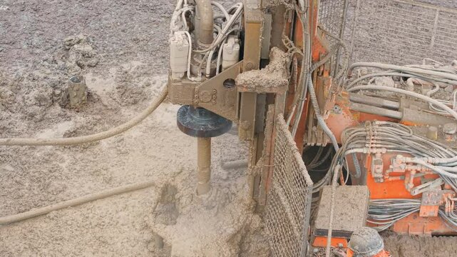 Construction equipment piling rig  drilling into wet ground at a building site. Rotating shaft and steam