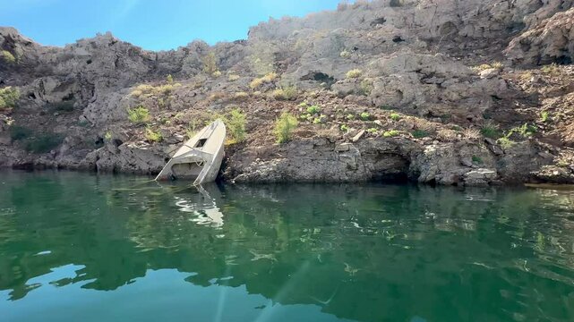 Dramatic drought effects at Lake Mead expose a haunting sunken boat, emerging from receding waters, highlighting the stark impact of historic low water levels on this once-thriving reservoir.