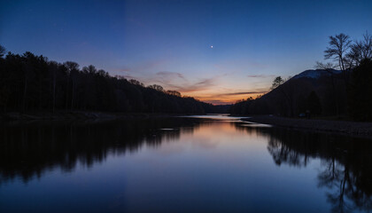 Fototapeta premium Serene river at sunset with mountains and trees