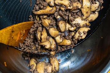 moving the stir-fried mushroom and beef from the frying pan to the bowl