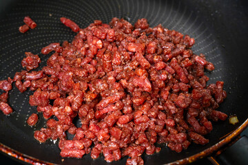 stir-frying the seasoned beef on the frying pan