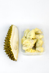 Pieces of fresh durian fruit are neatly arranged within a transparent plastic container. The golden-yellow durian pulp contrasts against the white background