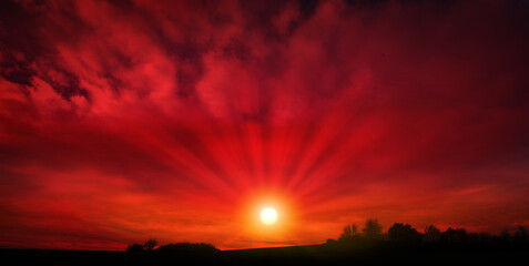 Red sunset background with sun and big abstract clouds.