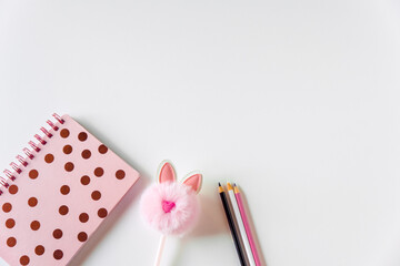 Stylish flat lay, beautiful women's notebook in polka dots, cute fluffy pen and pencils. feminine background, copy space