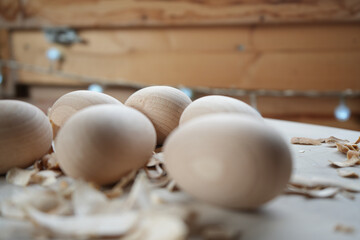 Close-up of wooden eggs with wood shavings on a light surface, highlighting natural textures, craftsmanship, and rustic aesthetics, perfect for themes of handmade crafts, woodworking, or minimal desig