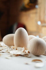 Close-up of wooden eggs with wood shavings on a light surface, highlighting natural textures,...