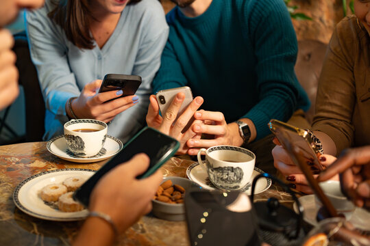 Close-up of hands using smartphones during coffee time at a cafe