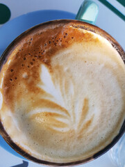 Close-up of a latte with foam art in a green mug