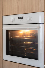 Modern built-in oven with illuminated interior in a minimalist kitchen design