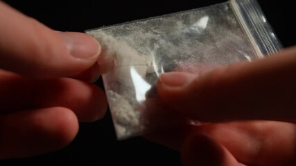 Drugs addicted person just purchased illegal Heroin or Fentanyl like powder substance from the dealer on the street and looking at it. Person ready to have a party. Illegal street drugs epidemic.