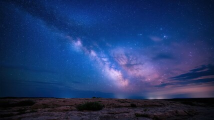 Fototapeta premium A stunning view of the Milky Way galaxy illuminating a rocky landscape under a starry night sky, creating a serene and tranquil atmosphere.