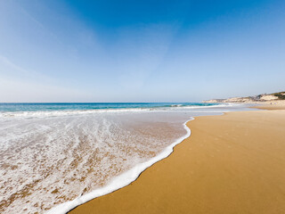 Low angle view of sandy beach, sea and blue sky