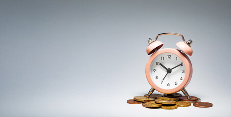 An alarm clock rests on a stack of coins, symbolizing the importance of time management in financial success. This composition emphasizes the connection between time and money.