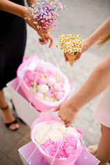 Three feminine hands of a girlfriends with a chic bouquets of summer flowers
