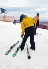 A skier prepares for a descent on a snowy slope, showcasing vibrant winter attire amidst a chilly...