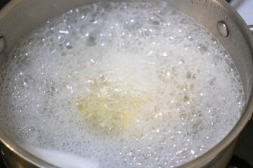 A close-up of boiling water in a stainless steel pot, creating a dynamic and vibrant visual with bubbles and steam, suggesting cooking and culinary exploration.